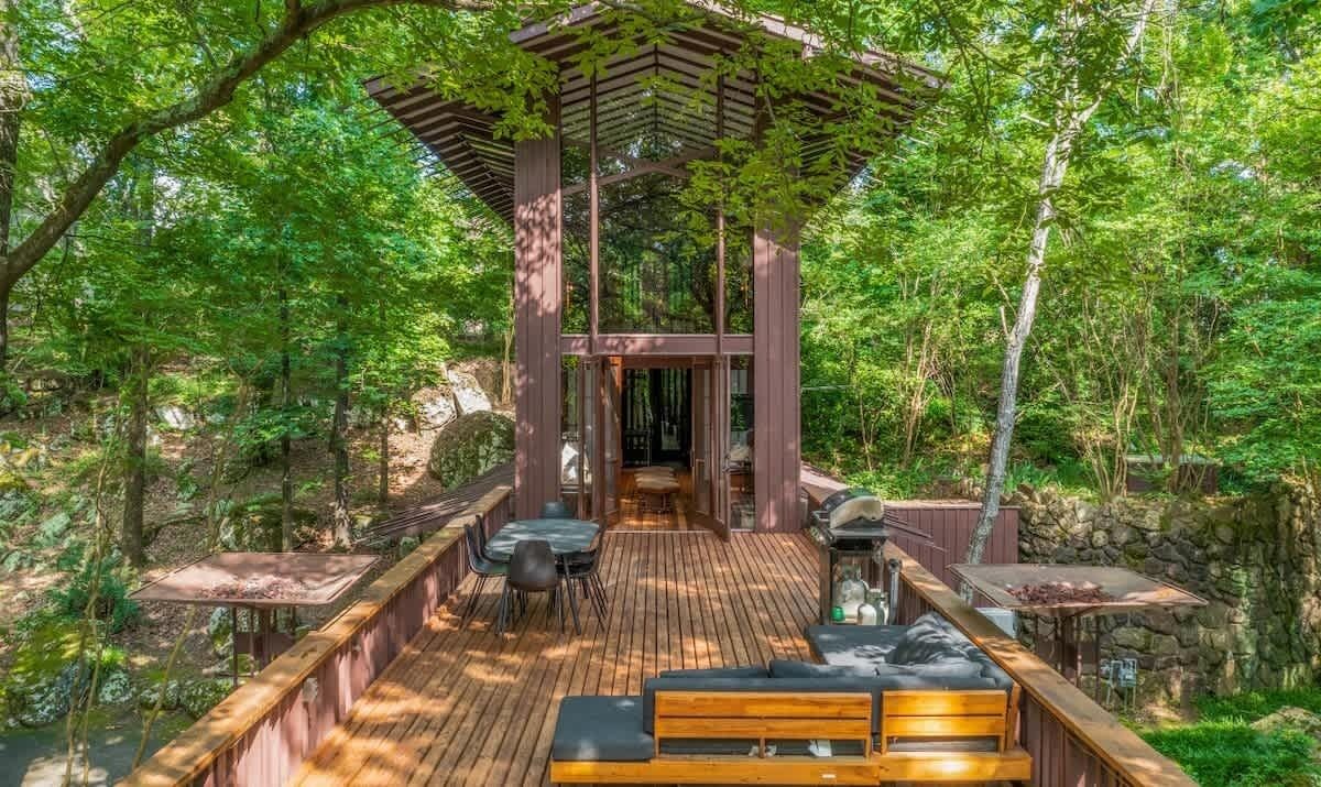 Eine Holzterrasse mit einer Pergola, Sitzgelegenheiten im Freien und einer Steinmauer.