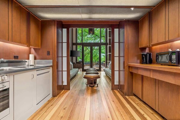 A modern kitchen with wooden cabinetry, a central island, and a view to an outdoor deck.