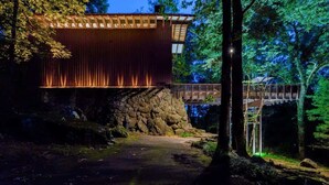 A wooden cabin with a stone foundation, a wooden deck, and a stone wall.