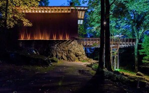 A wooden cabin with a stone foundation, a wooden deck, and a stone wall.