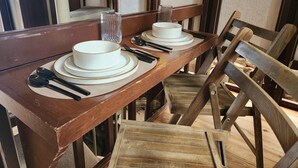Une table de salle à manger en bois, avec des assiettes, des couverts et des verres.