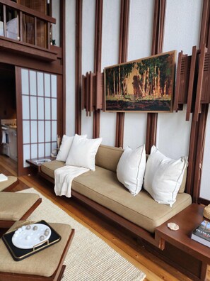 A traditional-style living room with a sofa, cushions, a painting, and wooden paneling.