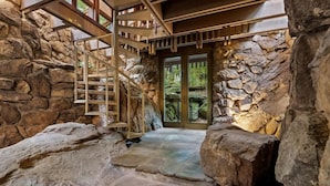 A stone-walled interior with a spiral staircase leading to a door.