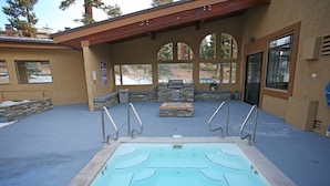A covered outdoor swimming pool with a stone bench and a stone wall.