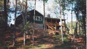 A cabin with a deck, surrounded by trees.