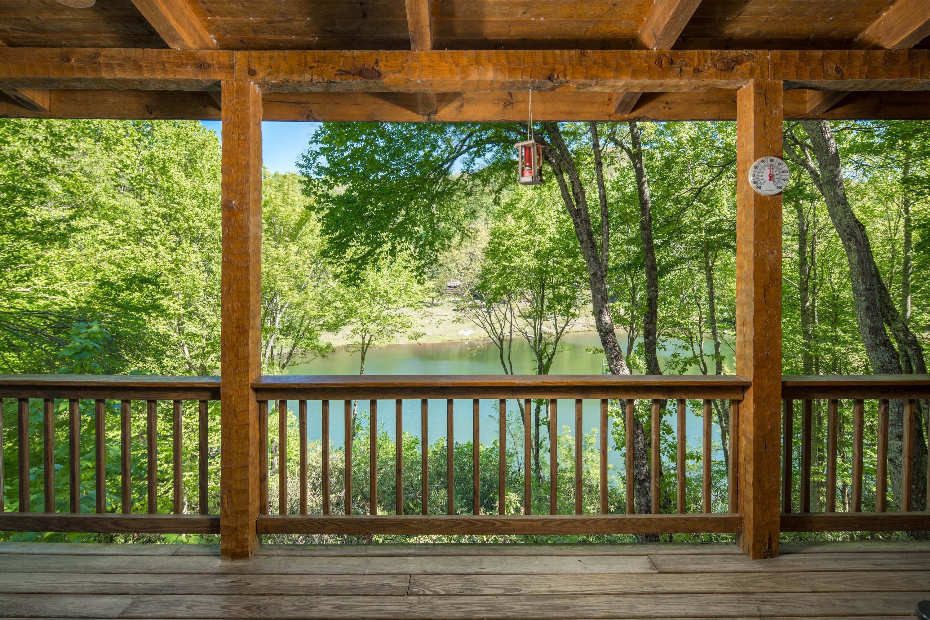 A wooden deck with a view of a lake surrounded by trees.