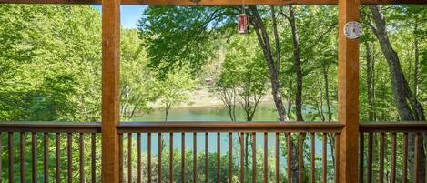 A wooden deck with a view of a lake surrounded by trees.
