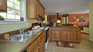 Una cocina con armarios de madera, estufa y pileta.