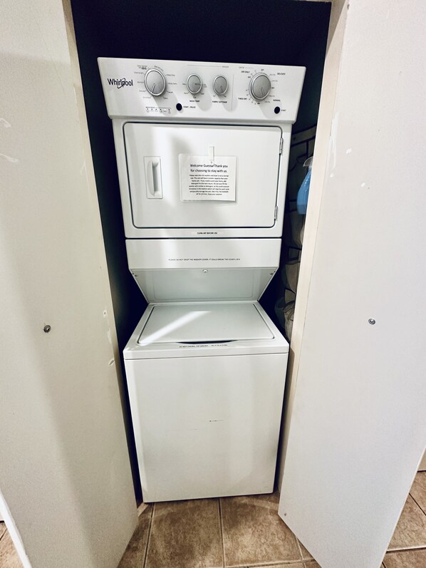 A Whirlpool washer and dryer unit with control knobs, a label with instructions, and a cautionary note about the washer cover.