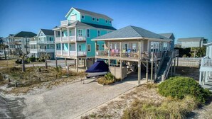 A beachfront property with a two-story house, a covered deck, and a boat. - This' L Do - Oceanfront - Upcycled Vintage Beach Cottage (North Topsail Beach)