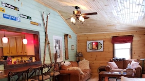 Ein gemütliches Blockhauskamin-Interieur mit Holzbalkendecke, einer Bar, einer Couch und einem gemusterten Teppich.