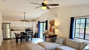 Una cocina moderna con armarios blancos, un refrigerador de acero inoxidable y un comedor con mesa y sillas de madera.