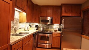 Eine Küche mit Holzschränken, Edelstahlgeräten, Granitarbeitsplatten und einem eingebauten Backofen.