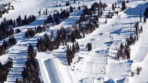 Une piste de ski enneigée, avec des remontées mécaniques et des arbres.
