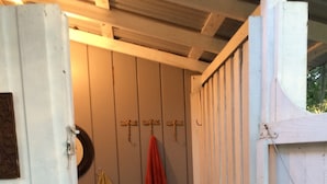 Et aflukke med bænk, kurv på væggen og en dør.