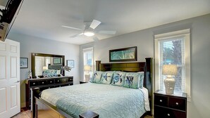 A bedroom with a bed, a dresser, a nightstand, a ceiling fan, and a window with blinds. - Come enjoy one of Port Aransas best hidden gems! Cozy condo, just a block from t (Port Aransas)