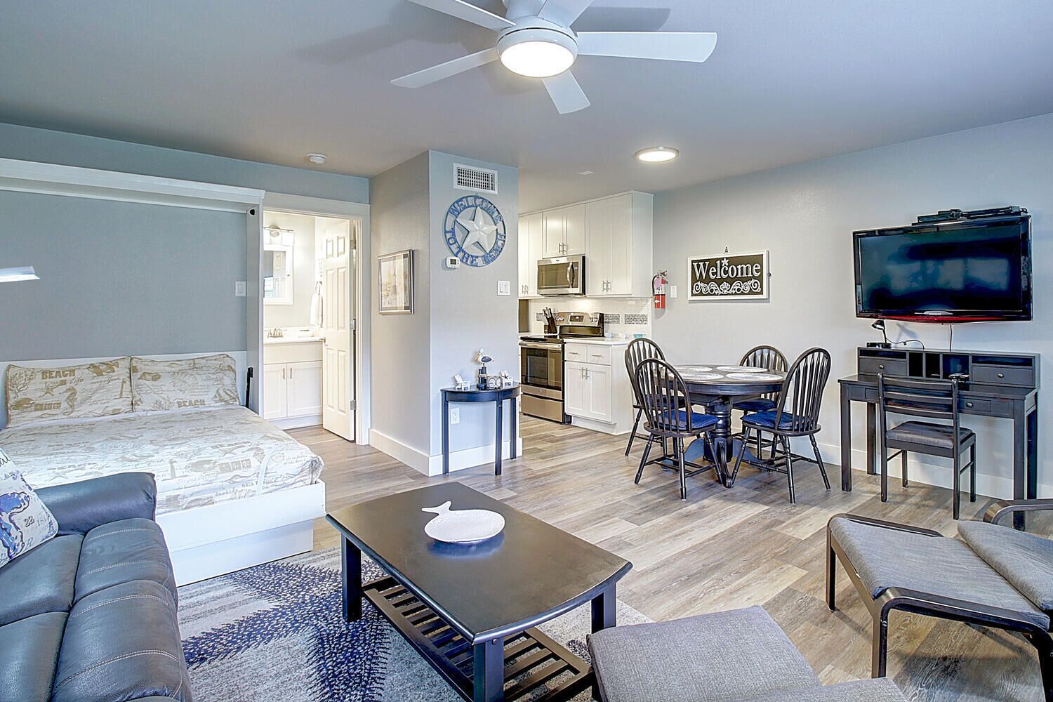 Un appartement moderne comprenant un salon, un coin repas, une kitchenette et un téléviseur fixé au mur.