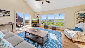 A spacious living room with a large window, a ceiling fan, and a cozy seating area. - Waterfront Beach Club Villa! 3 BR/3.5 BA! Luxury, Ocean view! Amenity access included! (Seabrook Island)