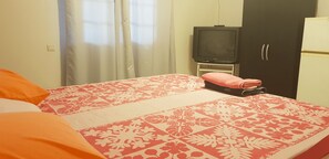 A bedroom with a bed, a television, a wardrobe, and a refrigerator.