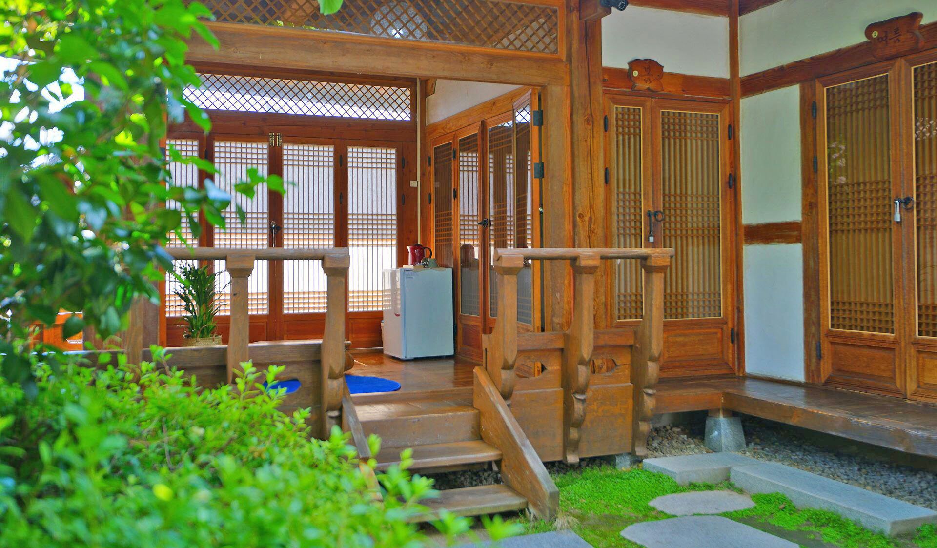 Una habitación tradicional japonesa con suelo de tatami, puertas correderas y una escalera de madera que lleva a un porche.