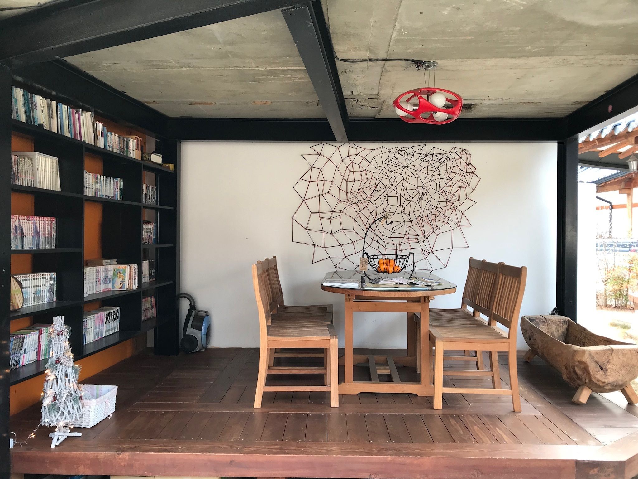 Un rincón acogedor para leer, con una mesa de madera, dos sillas y una estantería llena de libros.