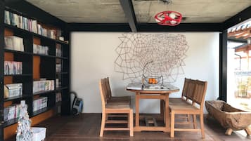 Un rincón acogedor para leer, con una mesa de madera, dos sillas y una estantería llena de libros.