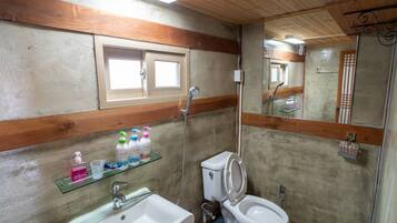 A bathroom with a sink, toilet, and shower. There is a window above the sink and a mirror above the toilet.
