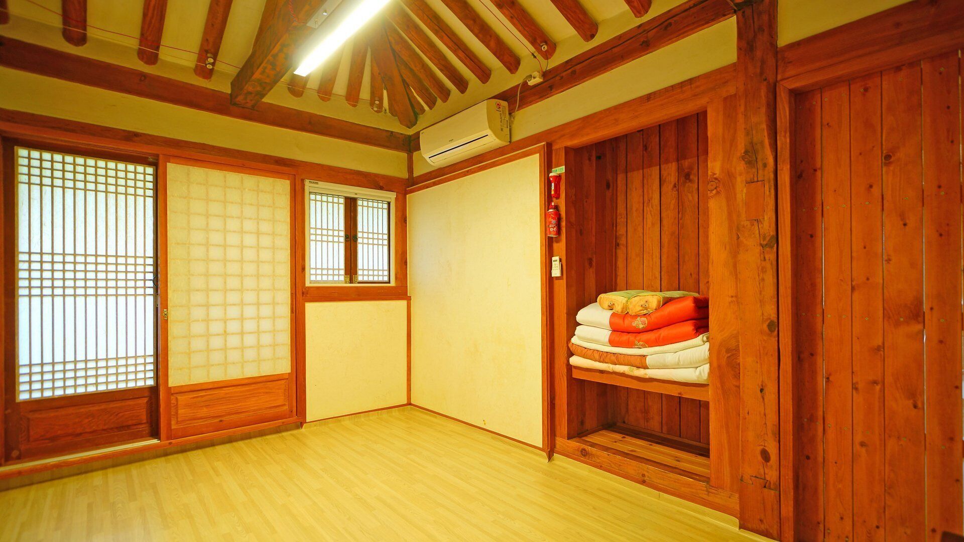 A traditional Japanese room with tatami flooring, sliding doors, and a built-in shelf with cushions.