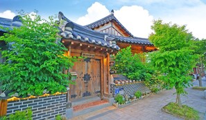A traditional Korean-style building with a wooden entrance, tiled roof, and a brick pathway leading to the door. - Sarangroo (Jeonju)