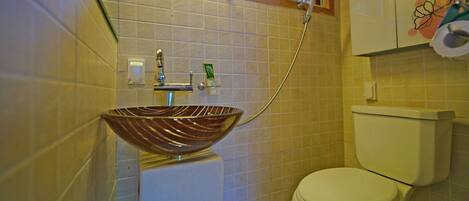 A bathroom with a vessel sink, a toilet, and a shower.
