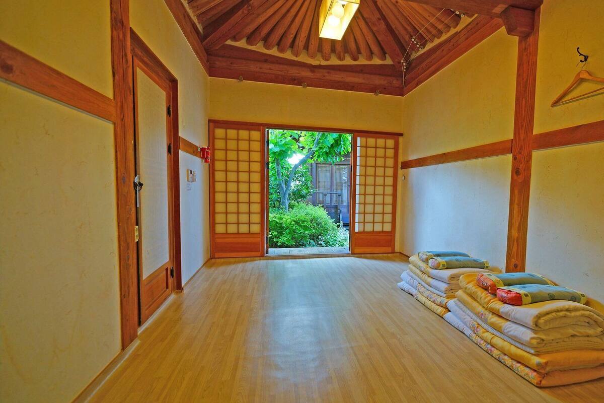 Una habitación japonesa tradicional con suelo de tatami, puertas correderas y vistas al exterior.