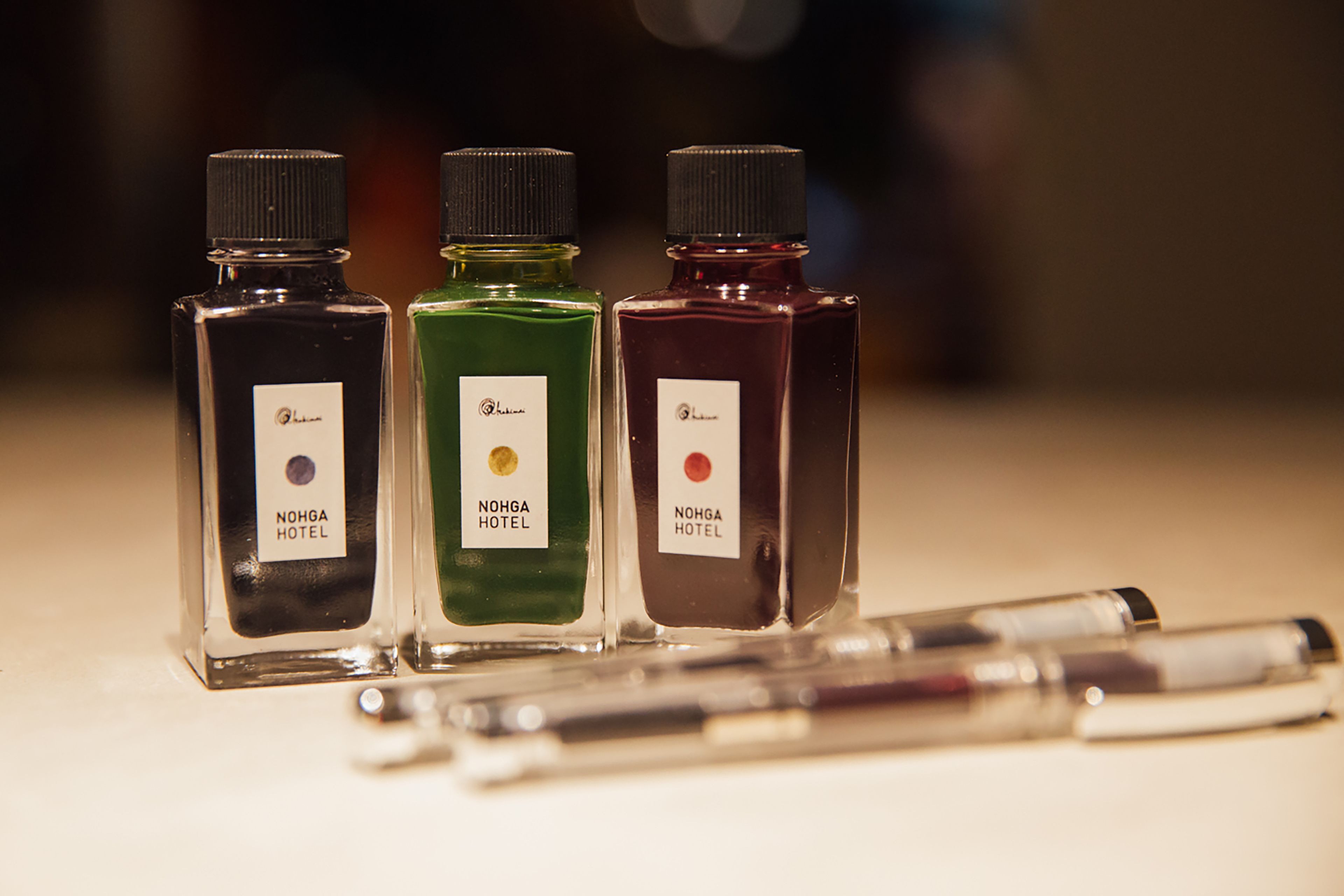 Tres botellas de colonia NoHGA Hotel sobre una mesa.