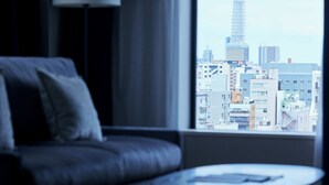 Una sala de estar moderna con vistas a un paisaje urbano, incluyendo una torre destacada.