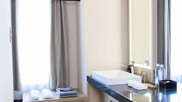 Un baño moderno con un espejo grande, un lavamanos blanco y un mueble de tocador de madera.