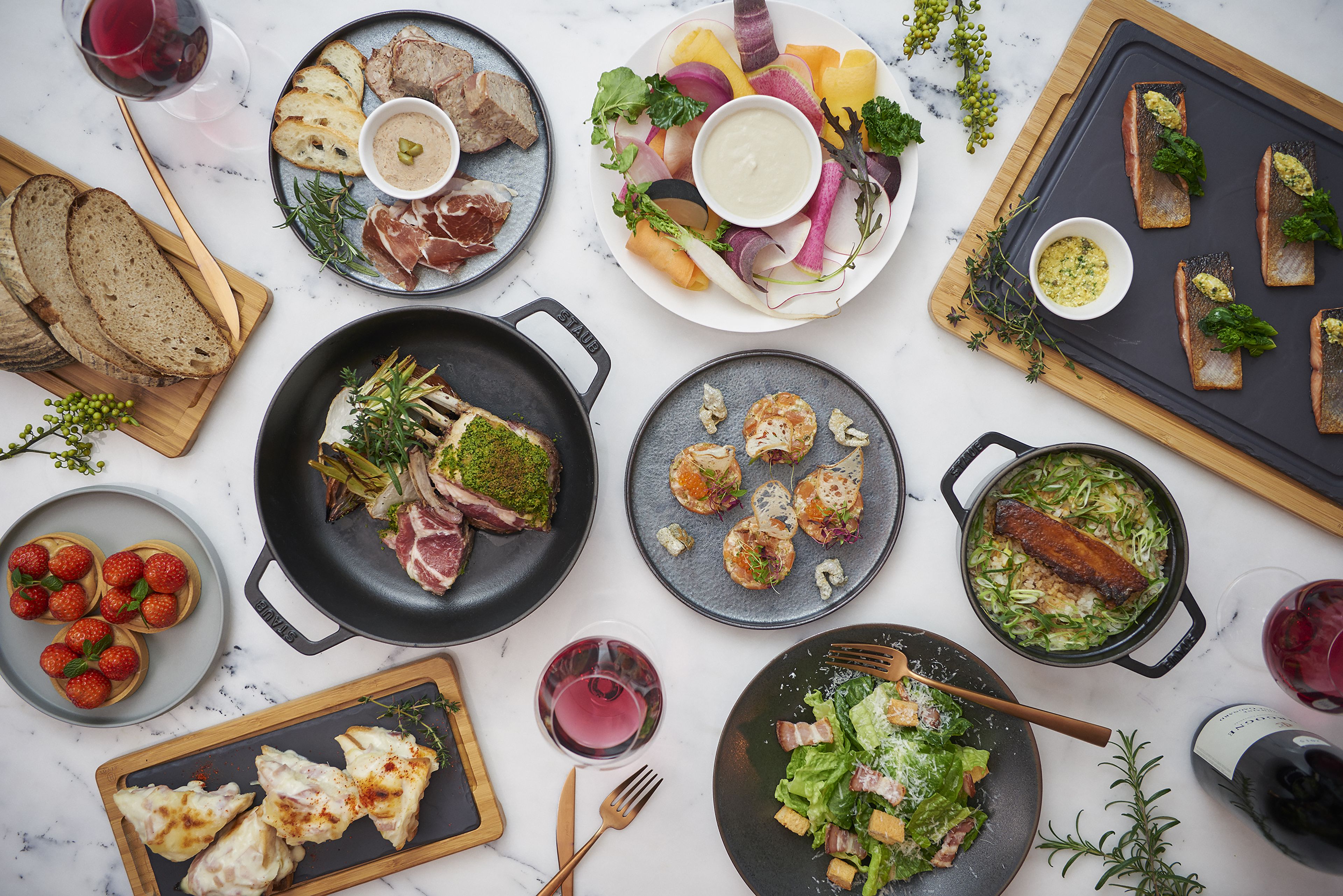 A variety of dishes and drinks on a table, including steak, fish, and salads.