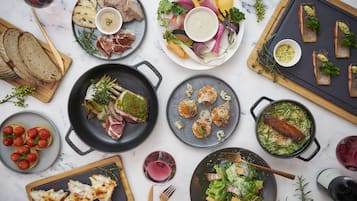 A variety of dishes and drinks on a table, including steak, fish, and salads.