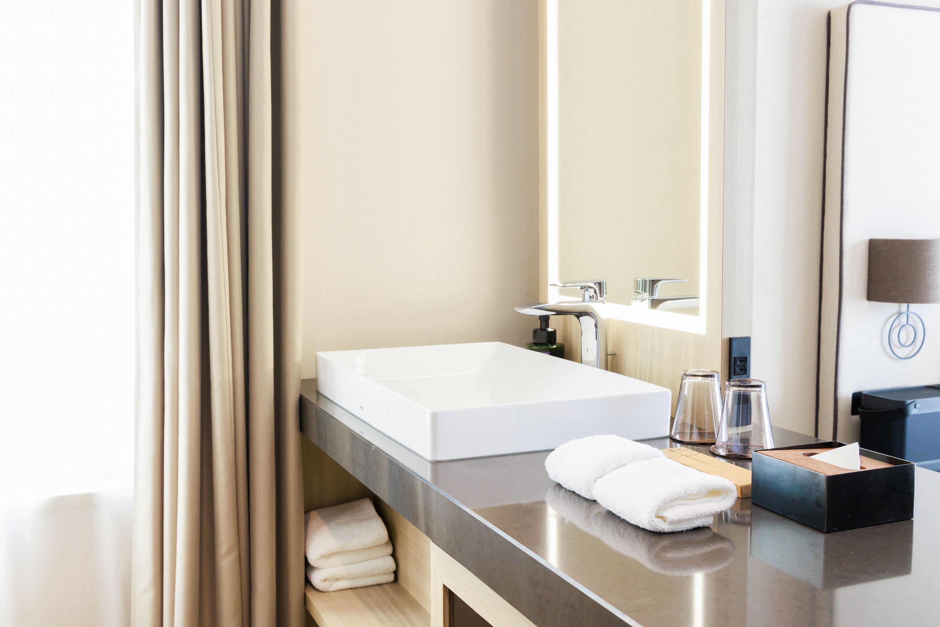 A modern bathroom with a large white sink, a mirror, and a towel rack.