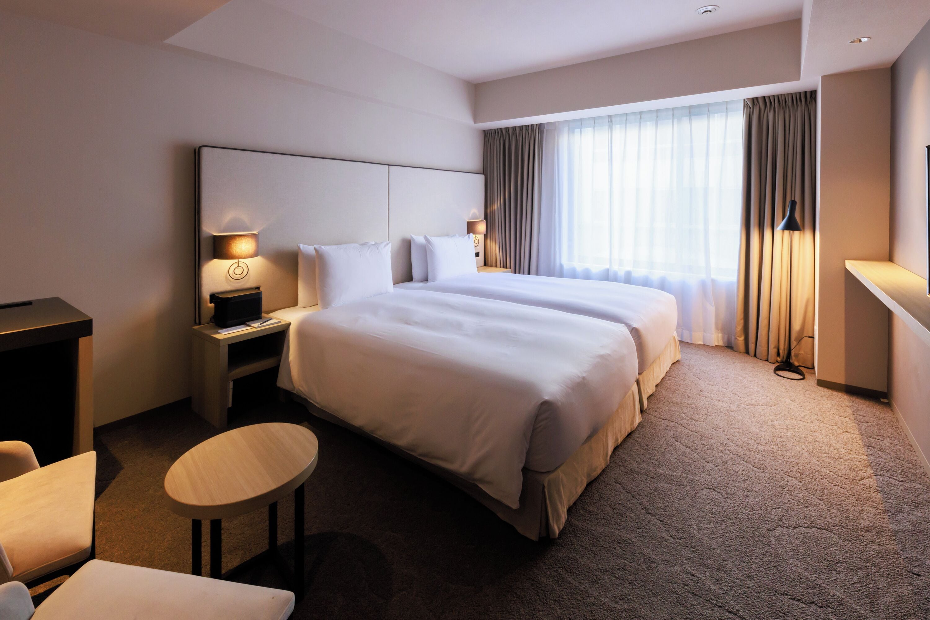 Ein Hotelzimmer mit einem großen Bett, zwei Nachttischen mit Lampen, einem kleinen runden Tisch und einem Fernseher.