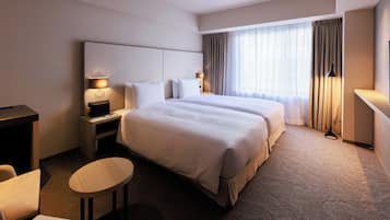 A hotel room with a large bed, two bedside tables with lamps, a small round table, and a TV.
