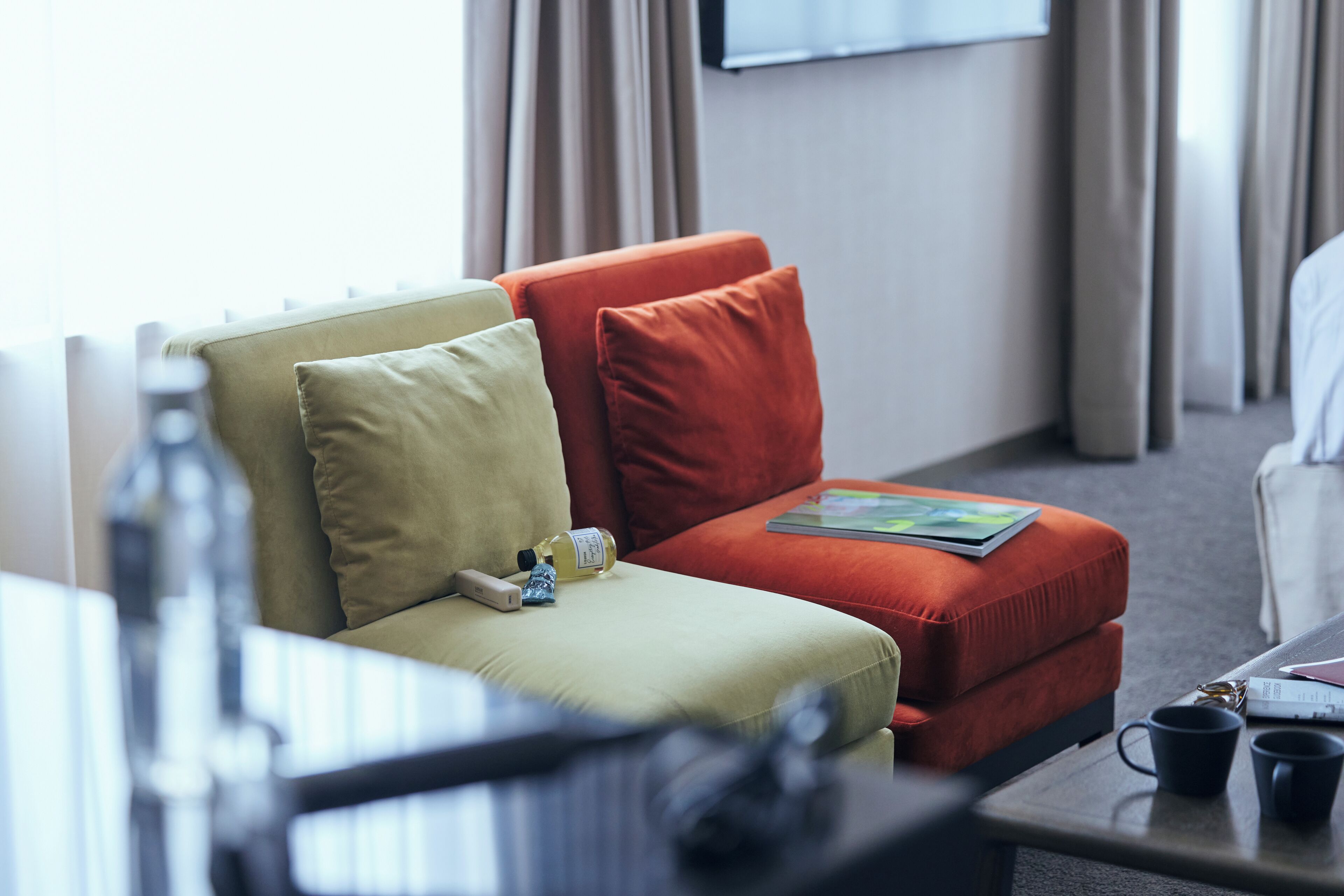 A hotel room with a sofa, a coffee table, and a television.