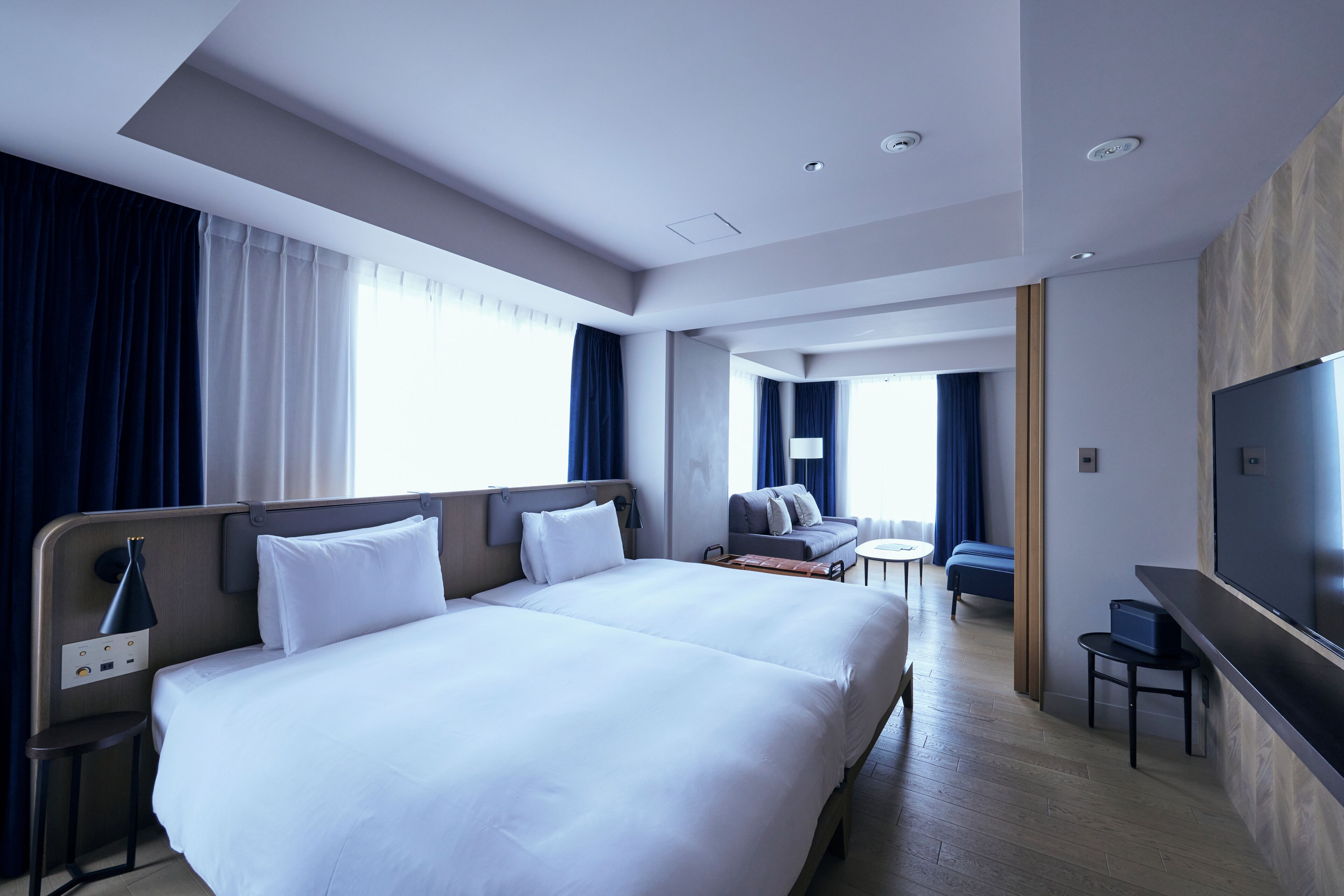 A modern hotel room with a large bed, a desk, and a TV.