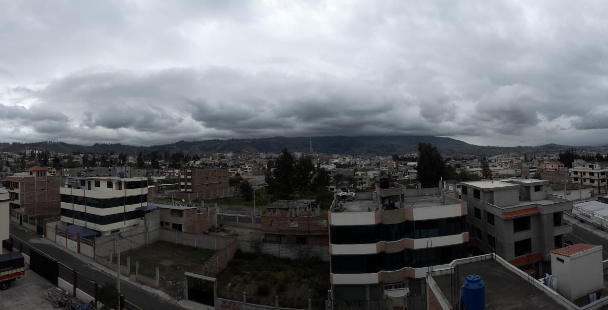 A residential area with multi-story buildings, some with balconies, under a cloudy sky.