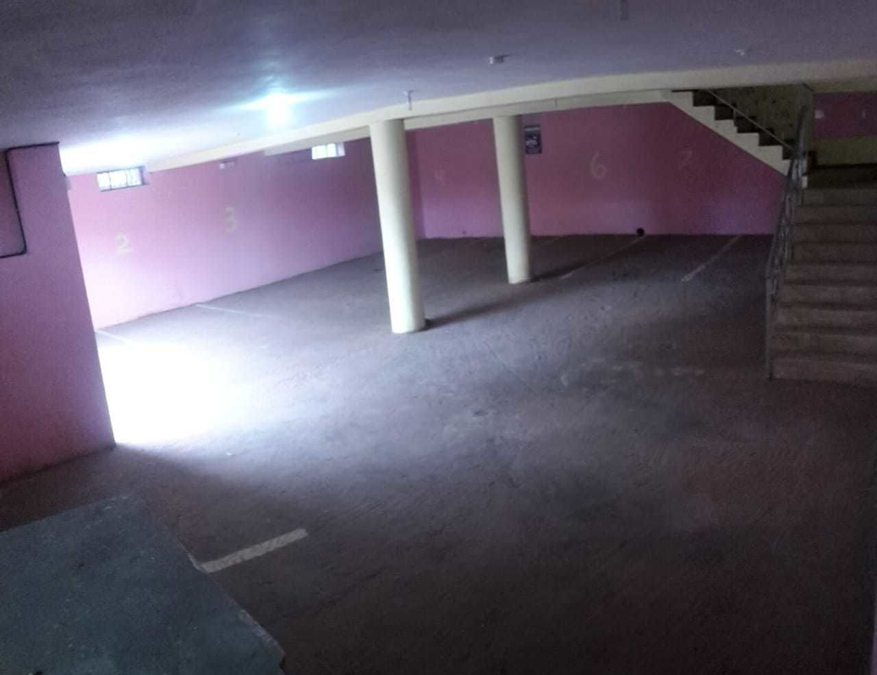 Een parkeergarage met betonnen vloeren, witte pilaren en paarse wanden.