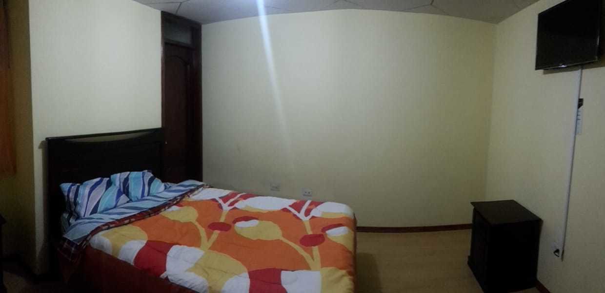 A bedroom with a bed, a television, and a speaker.