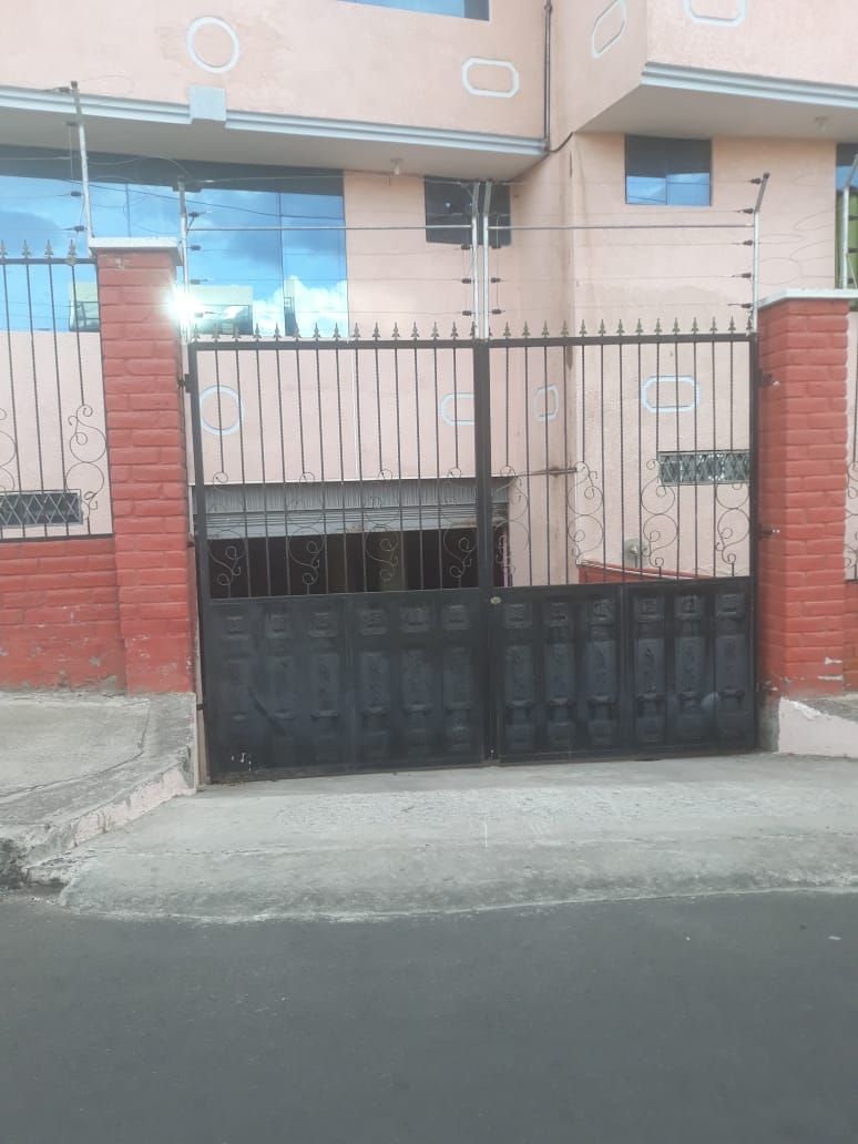 Una entrada protegida por un portón de metal y un muro de ladrillo.