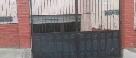 Une entrée fermée par un portail en métal et un mur en briques.