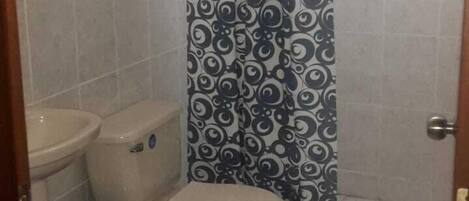 A small bathroom with a toilet, sink, and a shower curtain with a swirl pattern.
