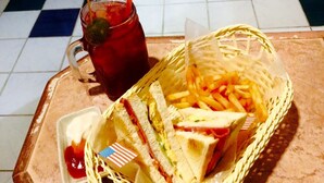 En bakke med en sandwich, pommes frites, en drik og en lille skål ketchup.