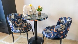 Una pequeña mesa redonda con cubierta de cristal y dos sillas con tapicería floral.