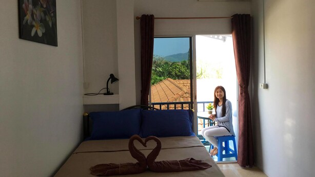 Un dormitorio con cama, escritorio, silla y vista al exterior.